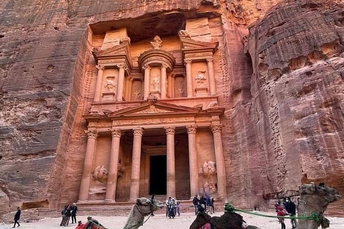 Visitors standing small in the Treasury forecourt at Petra, giving the facade its scale